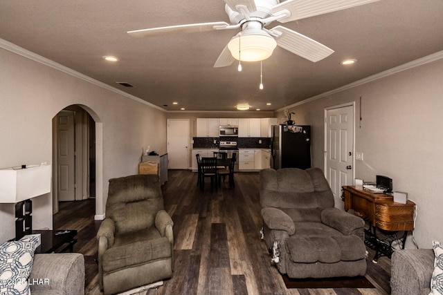 living area with crown molding, arched walkways, dark wood-style flooring, and ceiling fan