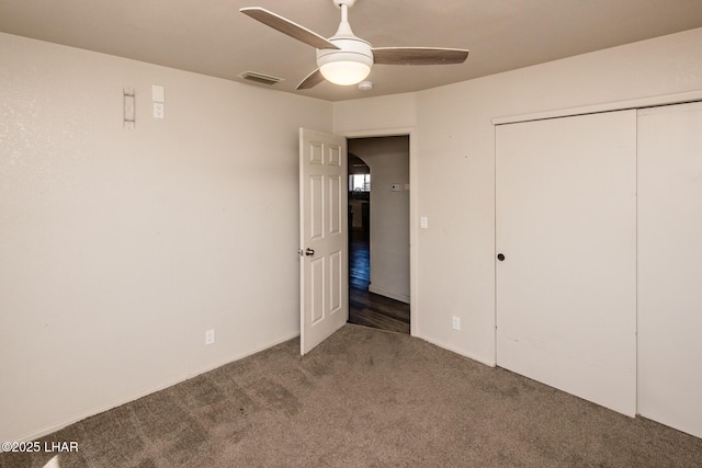 unfurnished bedroom featuring a closet, dark carpet, visible vents, and a ceiling fan