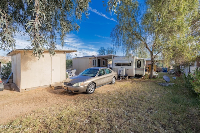 rear view of property featuring a yard, an outdoor structure, and a shed