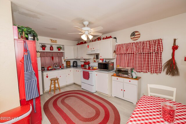 kitchen with stainless steel microwave, electric range, white cabinets, ceiling fan, and a sink
