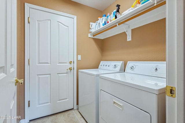 clothes washing area with laundry area, washing machine and clothes dryer, and light tile patterned floors