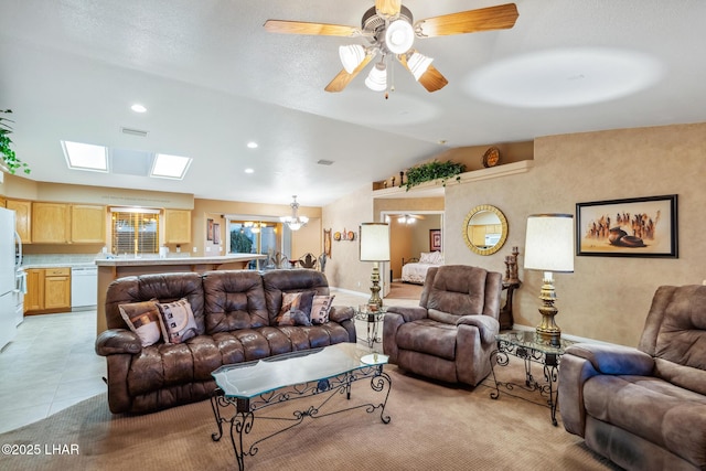 living room featuring vaulted ceiling with skylight, visible vents, ceiling fan with notable chandelier, light tile patterned flooring, and recessed lighting