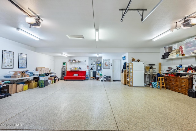 garage with water heater, a garage door opener, and freestanding refrigerator