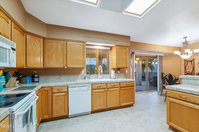 kitchen with decorative light fixtures, tile counters, a sink, a chandelier, and white appliances