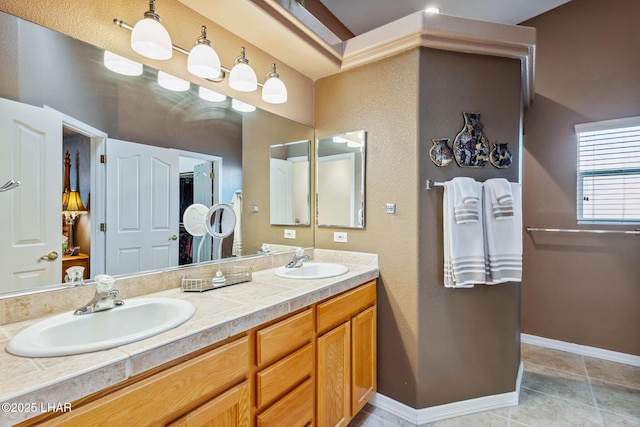 bathroom with double vanity, tile patterned flooring, baseboards, and a sink