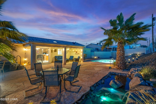 patio terrace at dusk with a fenced in pool and a fenced backyard