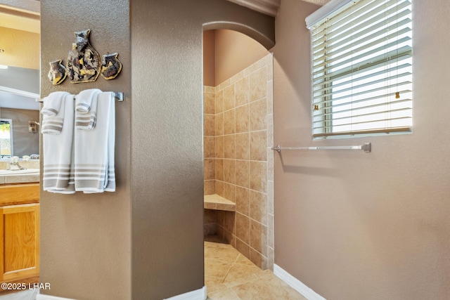 full bath featuring tile patterned flooring, baseboards, a walk in shower, and vanity