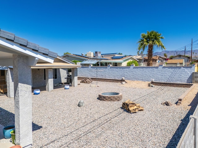 view of yard featuring a patio, a residential view, a fenced backyard, and an outdoor fire pit