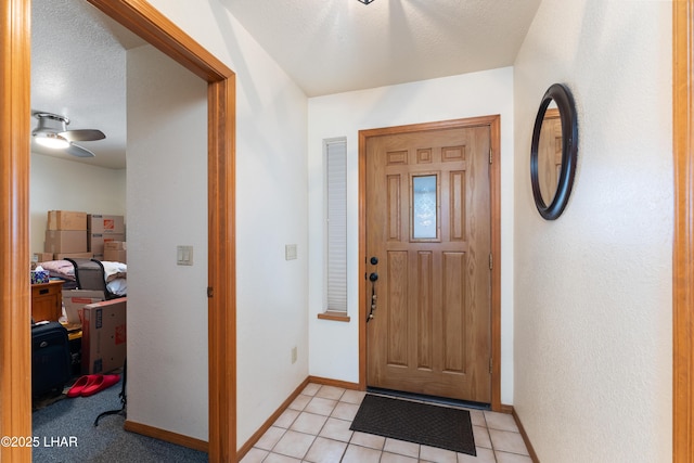 foyer entrance featuring light tile patterned flooring, ceiling fan, and baseboards