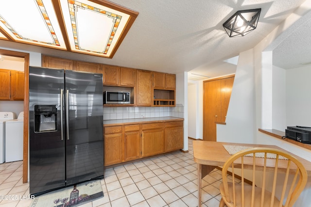 kitchen with separate washer and dryer, light tile patterned flooring, light countertops, stainless steel appliances, and brown cabinets