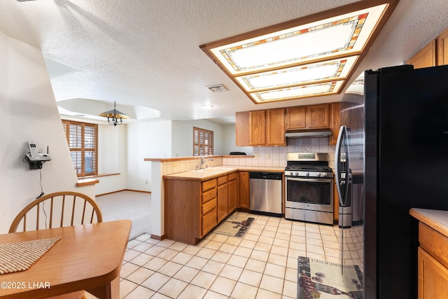 kitchen with visible vents, light tile patterned floors, appliances with stainless steel finishes, a peninsula, and under cabinet range hood