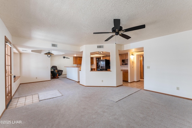 unfurnished living room with light colored carpet, baseboards, a ceiling fan, and visible vents