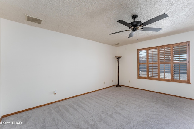 empty room featuring carpet flooring, visible vents, a textured ceiling, and baseboards