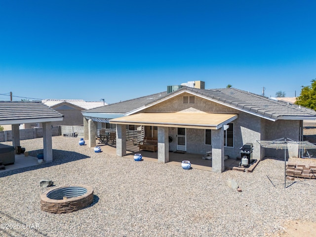 back of house with a fenced backyard, a fire pit, a patio, and stucco siding