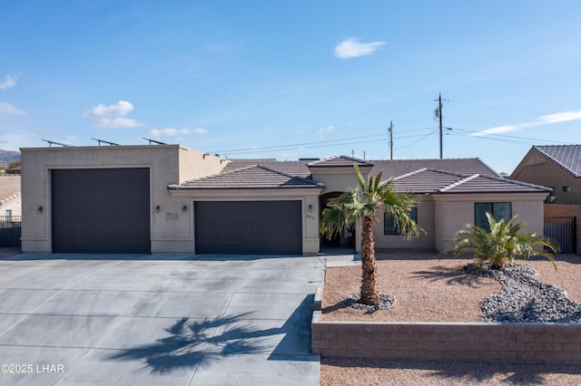 view of front of house with driveway, fence, an attached garage, and stucco siding