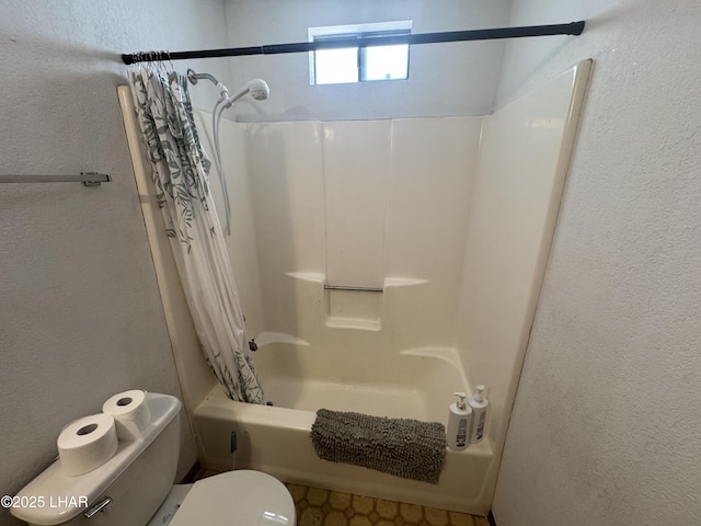 bathroom featuring toilet, a textured wall, and shower / bath combo with shower curtain