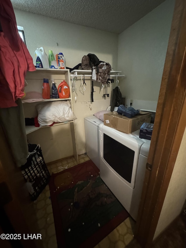 clothes washing area with laundry area, washing machine and dryer, and a textured ceiling