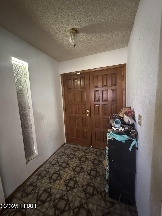 entryway with tile patterned floors, baseboards, and a textured ceiling