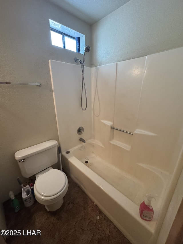 bathroom with washtub / shower combination, a textured wall, and toilet