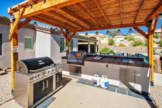 view of patio with exterior kitchen, a grill, and a pergola