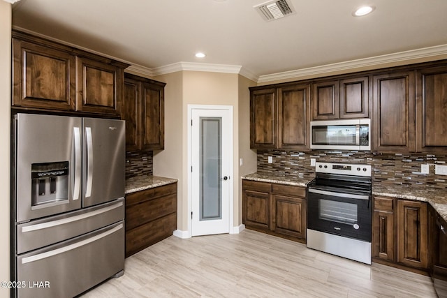 kitchen featuring dark brown cabinetry, visible vents, stainless steel appliances, and light stone counters