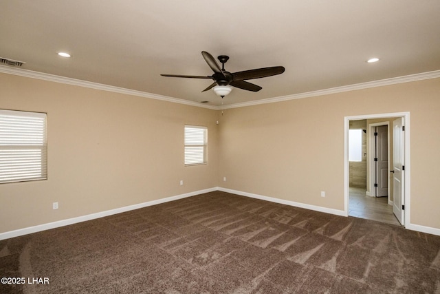 empty room with visible vents, crown molding, baseboards, and dark colored carpet