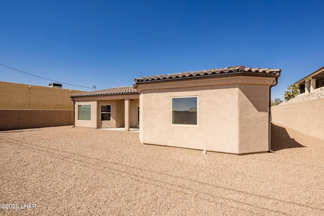 back of house featuring a patio, a tiled roof, a fenced backyard, and stucco siding