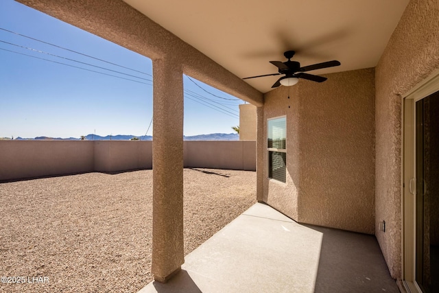 view of patio with a mountain view, a fenced backyard, and a ceiling fan