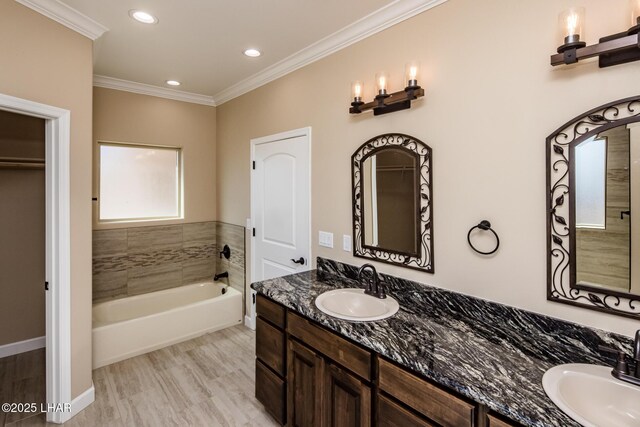 full bath featuring double vanity, crown molding, a garden tub, and a sink