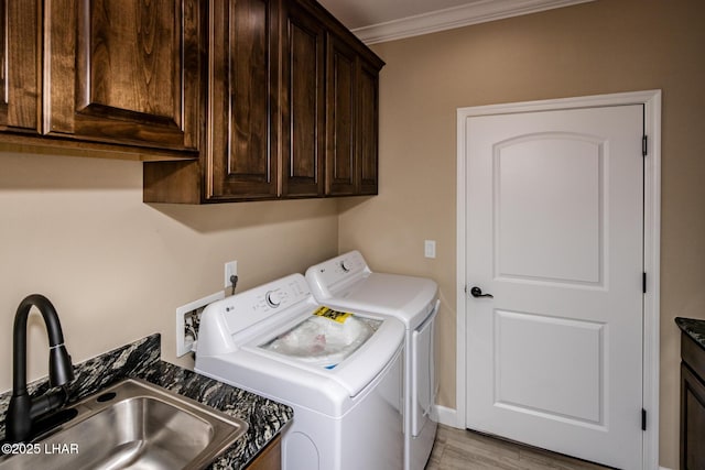 laundry area featuring light wood-type flooring, independent washer and dryer, ornamental molding, a sink, and cabinet space