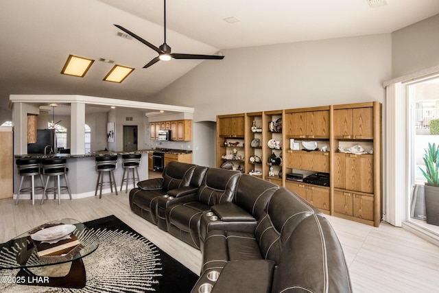 living area with a ceiling fan, visible vents, and high vaulted ceiling