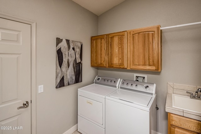 washroom with washer and dryer, cabinet space, and a sink