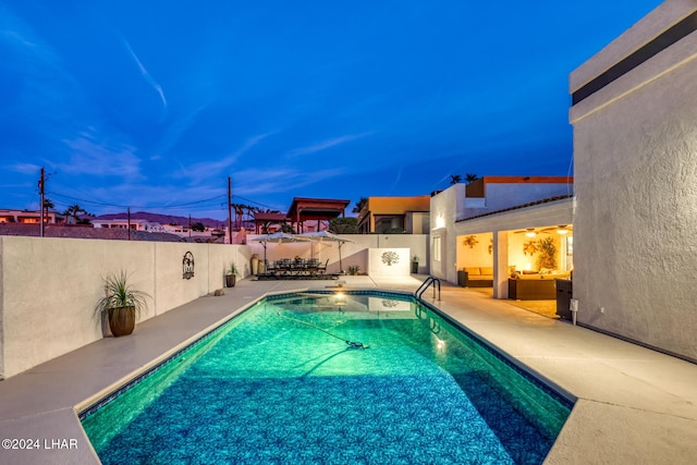 pool at dusk featuring a patio