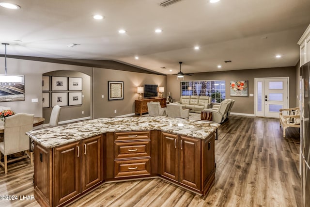 kitchen featuring a kitchen island, wood-type flooring, light stone countertops, and lofted ceiling