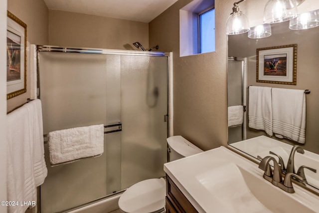 bathroom with vanity, toilet, and a shower with door