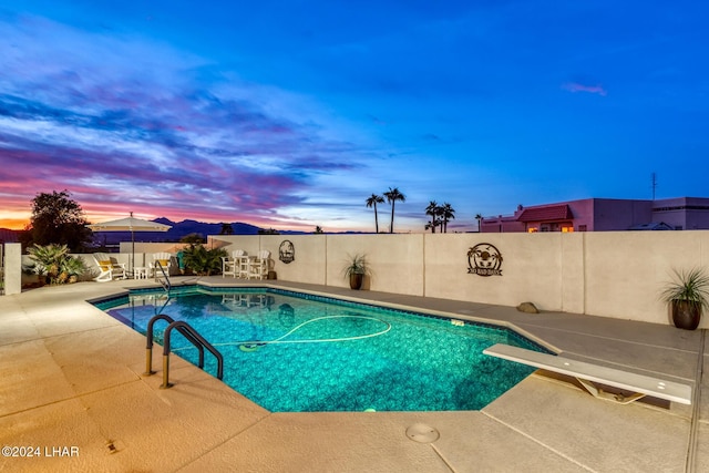 pool at dusk with a patio area