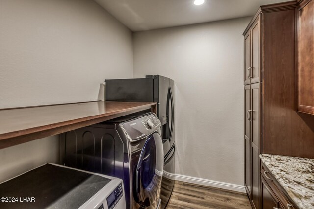 clothes washing area featuring cabinets, washing machine and dryer, and dark hardwood / wood-style floors