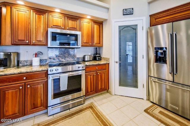 8839 Yaqui Loop, Parker, AZ 85344 - kitchen with appliances with stainless steel finishes, light stone countertops, light tile patterned floors, and brown cabinets