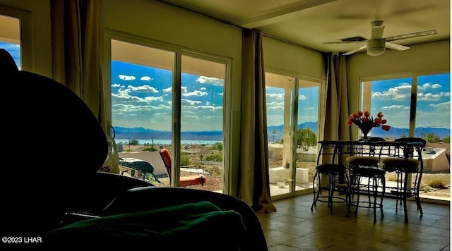 sunroom featuring ceiling fan, a healthy amount of sunlight, and a mountain view