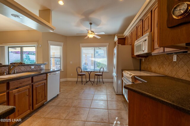 kitchen with sink, white appliances, a healthy amount of sunlight, and light tile patterned flooring