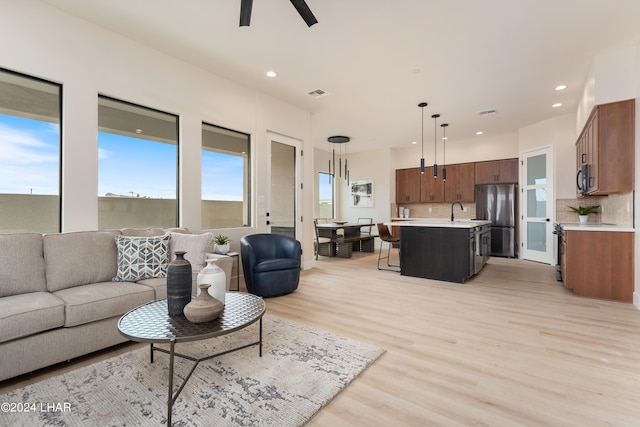 living room featuring ceiling fan, sink, and light hardwood / wood-style flooring