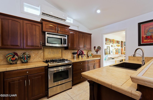 49605 Felspar Ave, Quartzsite, AZ 85346 - kitchen featuring stainless steel appliances, a wall unit AC, vaulted ceiling, backsplash, and light tile patterned floors
