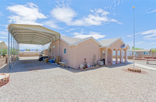 49605 Felspar Ave, Quartzsite, AZ 85346 - view of side of home featuring gravel driveway, stucco siding, and a carport