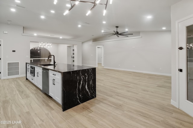 kitchen featuring stainless steel dishwasher, an island with sink, light wood-type flooring, and a sink