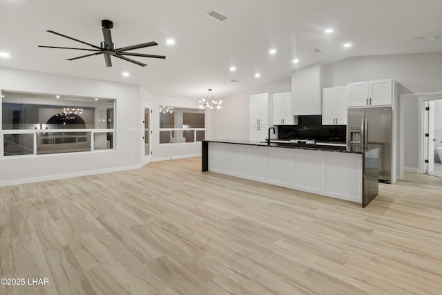 kitchen featuring dark countertops, lofted ceiling, open floor plan, a sink, and stainless steel fridge