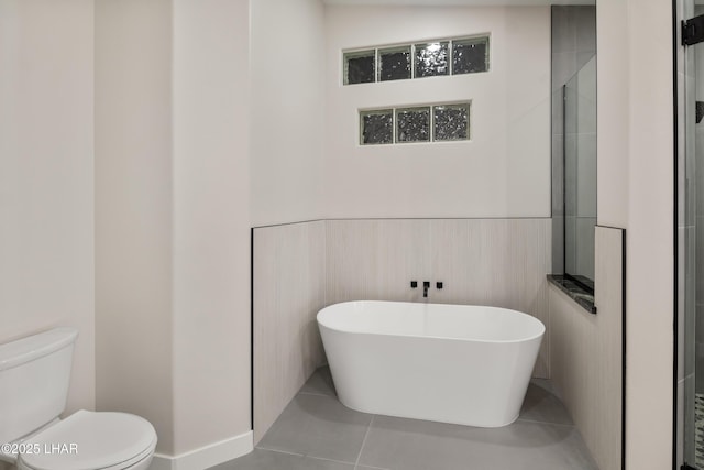 bathroom featuring a soaking tub, a tile shower, toilet, and tile patterned floors