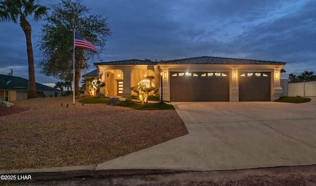 view of front facade featuring concrete driveway, a tile roof, an attached garage, fence, and stucco siding