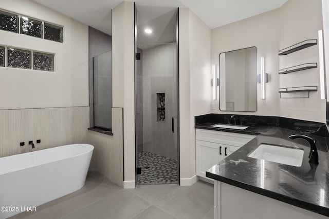 full bathroom featuring double vanity, a stall shower, wainscoting, a soaking tub, and a sink