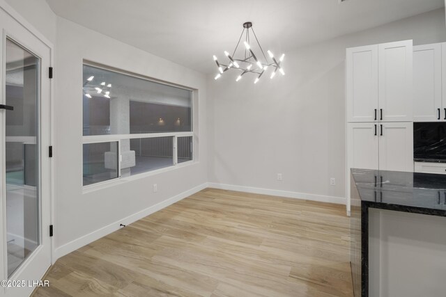 unfurnished dining area featuring light wood-type flooring and baseboards