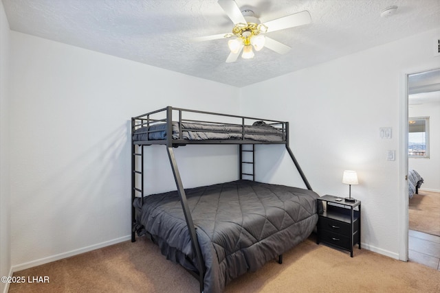 bedroom featuring a ceiling fan, baseboards, carpet floors, and a textured ceiling